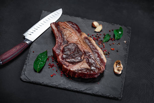istock Raw pickled meat beef steak with spices on black stone background 1315623112