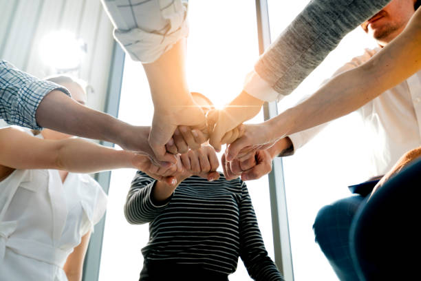 fermez-vous vers le haut de la vue supérieure des jeunes et des gens d’affaires d’énergie de fraîcheur mettant leurs mains fortes ensemble. pile de mains d’amitié. unité et concept réussi de travail d’équipe. - organized group leadership community business photos et images de collection