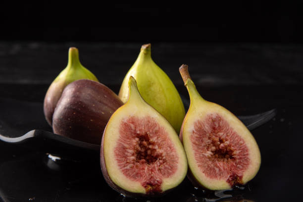 istock Purple figs, purple figs open on a black plate on dark reflective surface, black background, selective focus. 1315633910