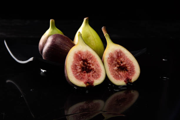 istock Purple figs, purple figs open on a black plate on dark reflective surface, black background, selective focus. 1315633913