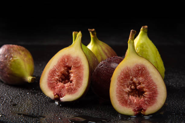 istock Purple figs, open purple figs being sprayed with water, black background, selective focus. 1315633971