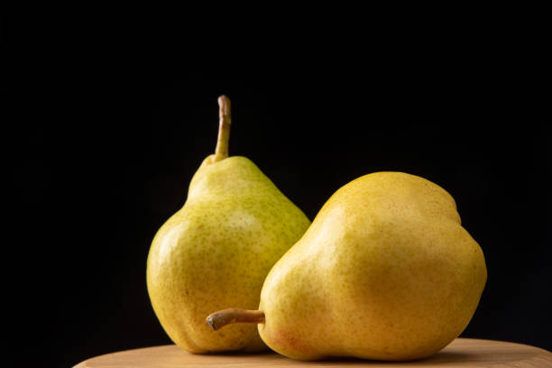 istock pears positioned on round wood, black background, selective focus. 1315634114