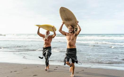 Happy friends with different age surfing together - Sporty people having fun during vacation surf day - Extreme sport lifestyle concept