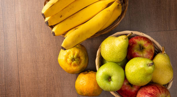 istock tropical fruit basket in detail on wooden surface, black background, selective focus. 1315635392