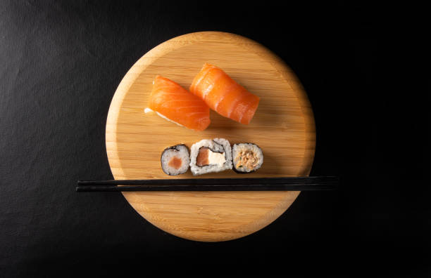 Sushi, beautiful sushi arrangement made of wood on dark surface, black background, top view.
