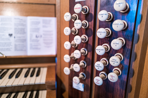 Macro close up depicting different knobs and controls of a church organ inside an old English Anglican church.