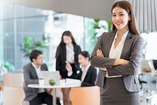 portrait Asian business people standing with confident and cheerful with business teamwork meeting brainstorm with laptop and paper document modern office background
