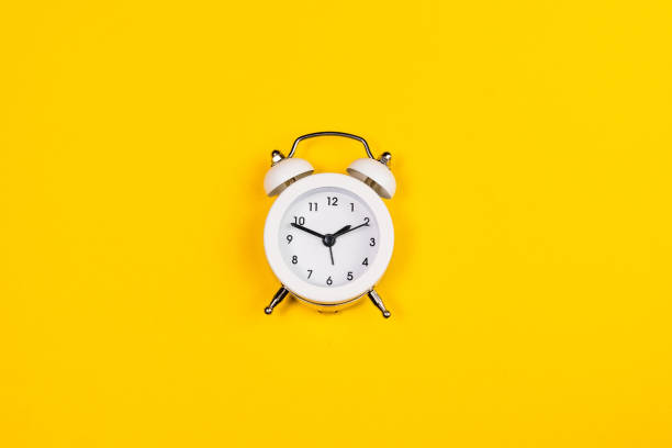 istock white alarm clock on yellow background. copy space. flat lay 1315652527