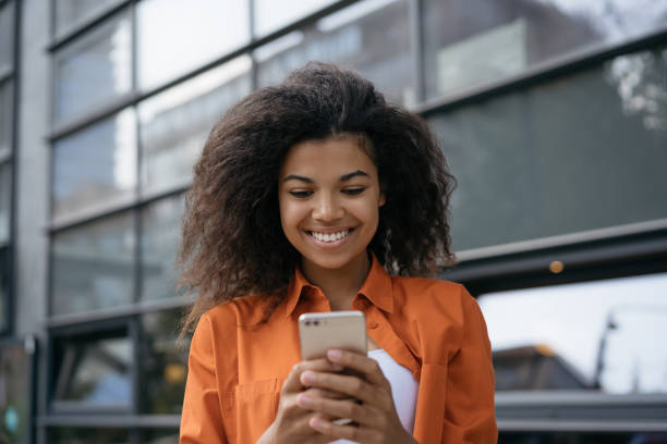 African American woman using mobile app for online shopping standing on the street Smiling African American woman using mobile app for online shopping standing on the street 18 19 years photos stock pictures, royalty-free photos & images