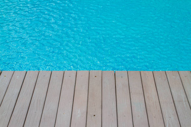 istock Artificial wood balcony, The gray-colored modeled shera partition board beside the pool with a bright blue water as the background. 1315661842