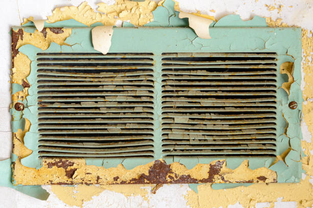 Old old air vent in an abandoned school. Paint is peeling around it, and metal is rusty.