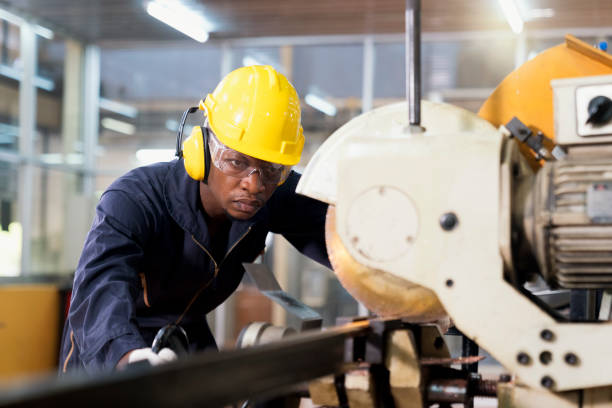 A factory mechanic is using a chainsaw to cut copper pipes. An expert technician is inspecting industrial machinery in a steel factory.