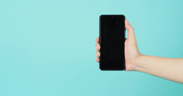 istock Empty Hand holding mobile phone guesture on green and blue or mint background. 1315671664
