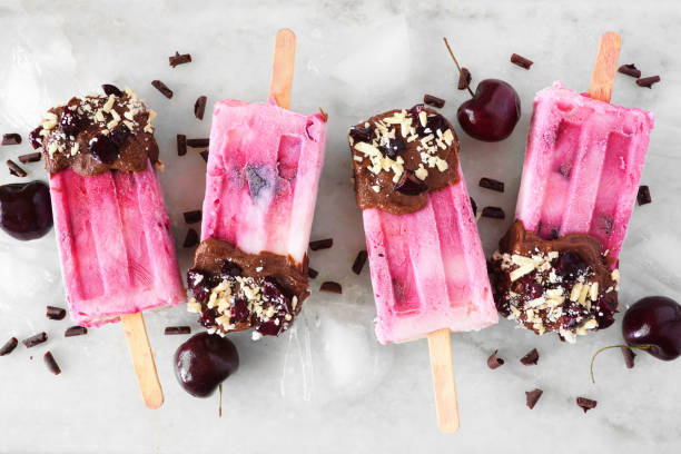 istock Chocolate and almond dipped cherry popsicles in a row over white marble 1315675126