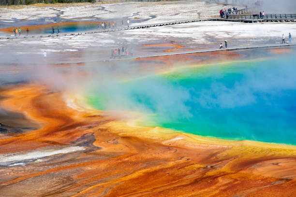 Visitors look at the Grand Prismatic Spring in Yellowstone National Park in Wyoming, USA on a sunny day.