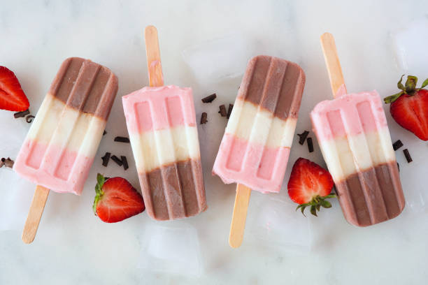 istock Group of neapolitan ice pops in a row on a white marble background 1315676607