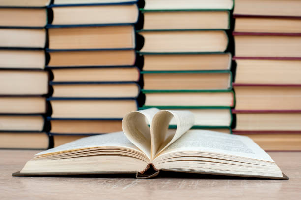 istock Open book, heart made from book sheets.Solid books on a wooden table. Education. 1315692793