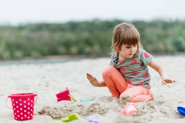 istock Four year old girl playing in sand on beach 1315697720
