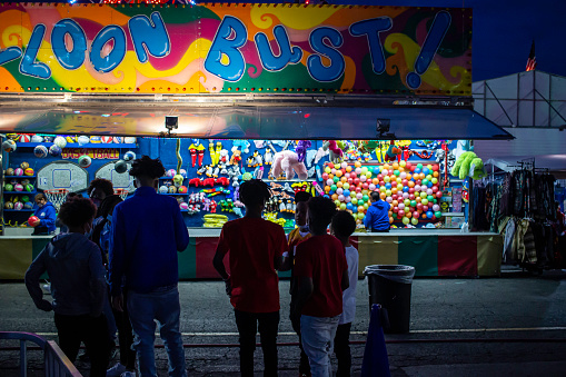 April 17, 2021 - Madison, Tennessee, U.S.: Teenagers hangout on the carnival midway located in the parking lot of a strip mall.