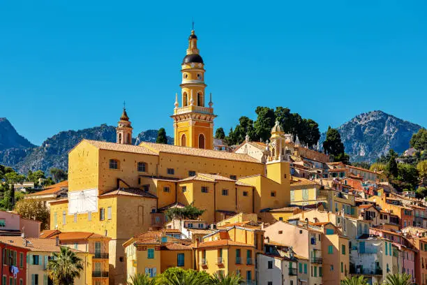 View of colorful houses and belfry of the Saint Michel Archange basilica in old town of Menton - small town on French Riviera.