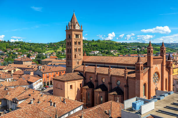 San Lorenzo Cathedral as seen from above in Alba, Italy. San Lorenzo Cathedral (aka Duomo) among old houses with red roofs in Old Town as green hills on background in Alba, Piedmont, Northern Italy. alba italy photos stock pictures, royalty-free photos & images