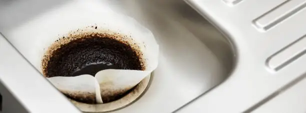 Coffee filter paper draining in kitchen sink plughole UK