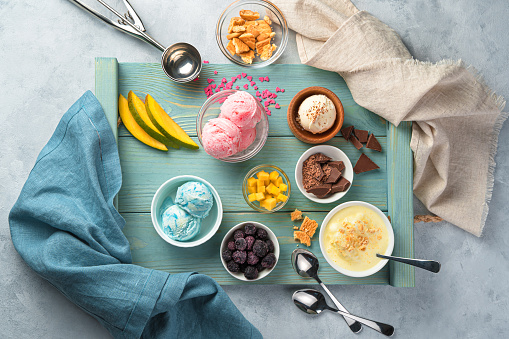 Different types of ice cream and toppings on a blue tray. Top view. Summer desserts.