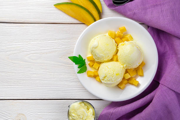 istock Creamy fruit dessert, mango ice cream and fresh mango on a white and purple background with space to copy 1315709569