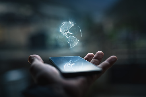 Earth hologram above smartphone screen blurred background