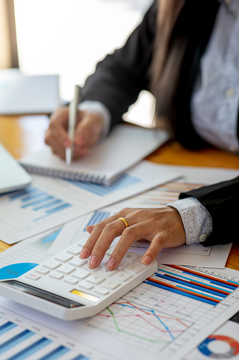 Close up of Business using calculator and laptop for do math finance on wooden desk, tax, accounting, statistics and analytical research concept