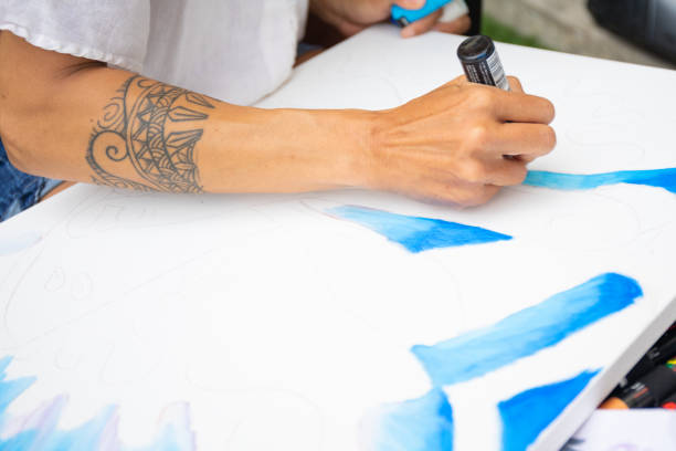 istock Close up of a tattooed arm drawing on canvas 1315765832