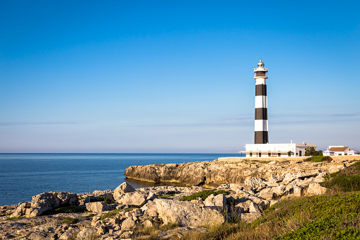 MINORCA ISLE - SPAIN - CIRCA AUGUST 2020: scenic Artrutx Lighthouse at sunset, famous landmark of the Isle