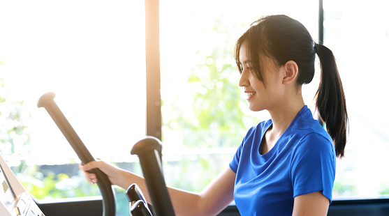 Asian Woman exercising on elliptical Machine Cross Trainer