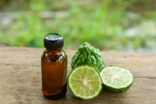 Bergamot oil in bottle and fresh bergamot fruit on wooden table with blur background.