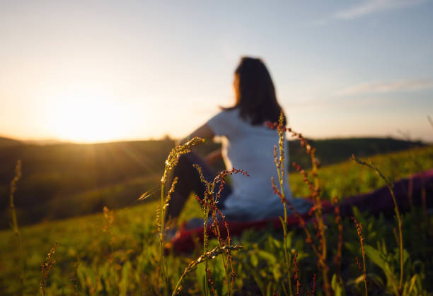 Blurred image of woman sitting in meadow in sunset