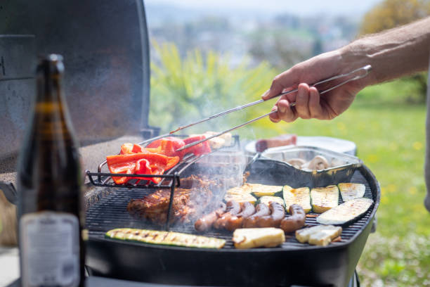 BBQ on weekend. Sausages, steak, cheese and vegetables on gas grill. Outdoors. stock photo