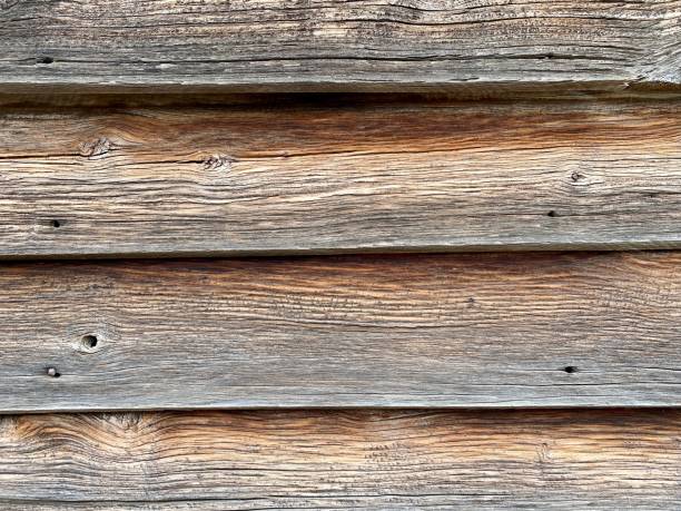 Horizontal closeup photo of a section of old, timber wall with cracked, rustic horizontal wooden planks