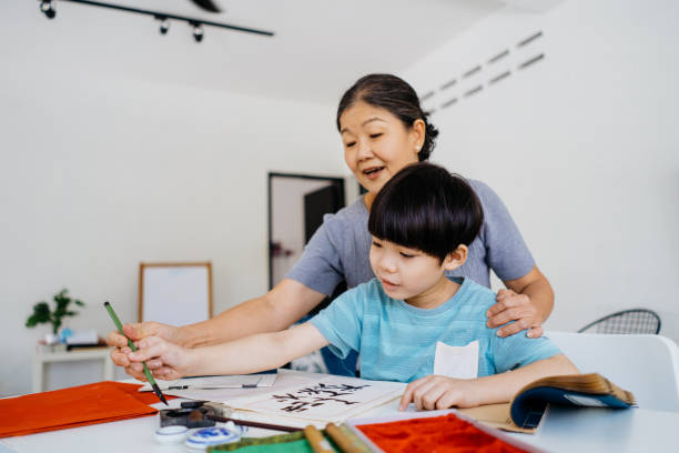 senior asian woman teaching her grandson chinese calligraphy - chinese script text calligraphy grandmother imagens e fotografias de stock