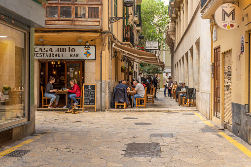 Palma de Mallorca, Spain; april 23 2021: Restaurant terrace full of diners at noon in the historic center of Palma de Mallorca. Use of face mask and safety distance due to the Coronavirus pandemic