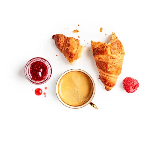 Coffee cup, fresh croissant and raspberry jam creative layout on white background. Healthy eating and sweet food concept. Good morning breakfast. Flat lay, top view. Design element