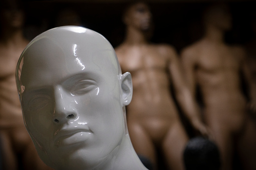 A male mannequins head is with defocused other mannequins.
