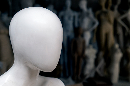 A recognizable dummy's head in front. There are grub of mannequins body behind her. They are isolated with black background.