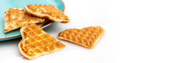 istock Heart shaped waffles standing scattered in green plate on white marble table 1315835282