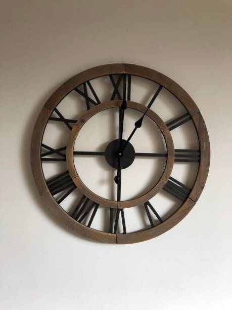 istock Large wooden clock on cream coloured wall 1315835616