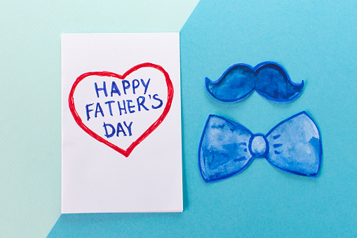 Father Day Concept. Funny mustache, bow tie and heart Card with the inscription: Happy Father's Day on a minimal blue background