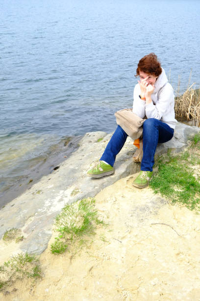 istock Woman is sitting on the stone on lakeshore 1315843236