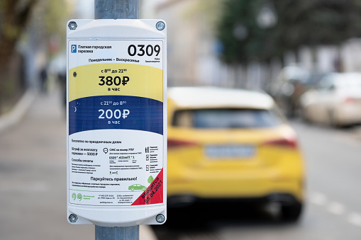 Moscow, Russia - MAY 01, 2021: The sign of the expensive paid Parking zone in the center of Moscow with a blurred yellow taxi car on the background