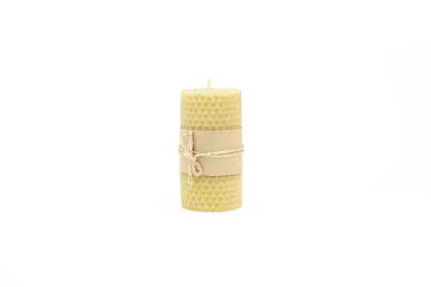 Beeswax candle made by hand. Beeswax candle with craft blank label and rope isolated on white background with copy space.