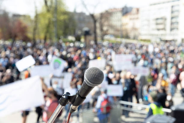 istock Protest or public demonstration, focus on microphone, blurred crowd of people in the background 1315847270