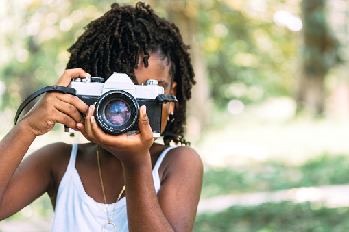 portrait of a small young African girl holding a camera and taking a photo.
